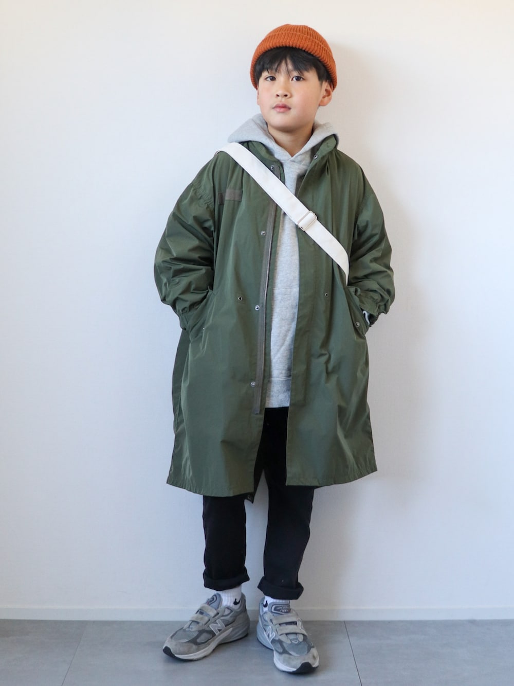 グリーン系のモッズコート、グレー系のパーカー、ブラック系のパンツを着用したキッズの冬コーディネートの3枚目の写真