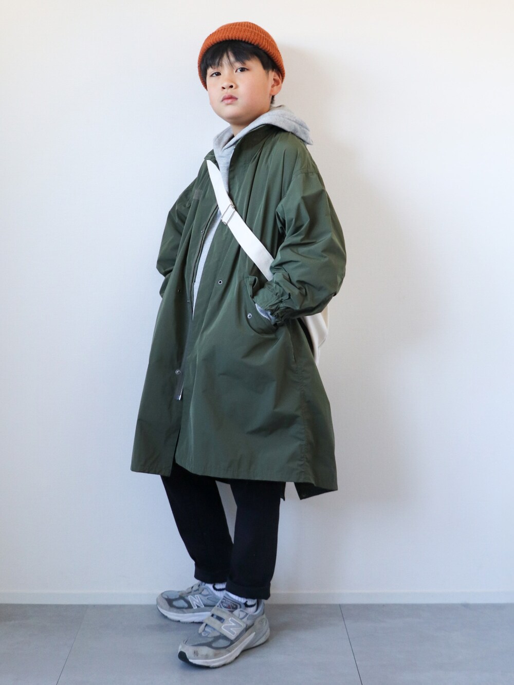 グリーン系のモッズコート、グレー系のパーカー、ブラック系のパンツを着用したキッズの冬コーディネートの4枚目の写真
