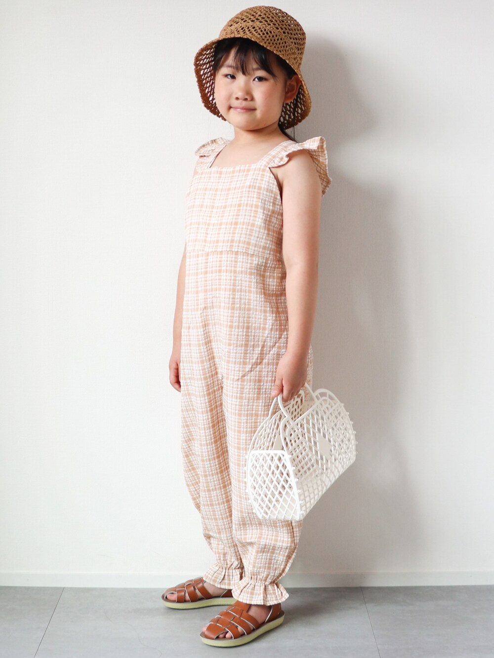 ベージュ系のサロペット/オーバーオール、ベージュ系のキャミソール、ブラウン系のサンダルを着用したキッズの春コーディネートの3枚目の写真