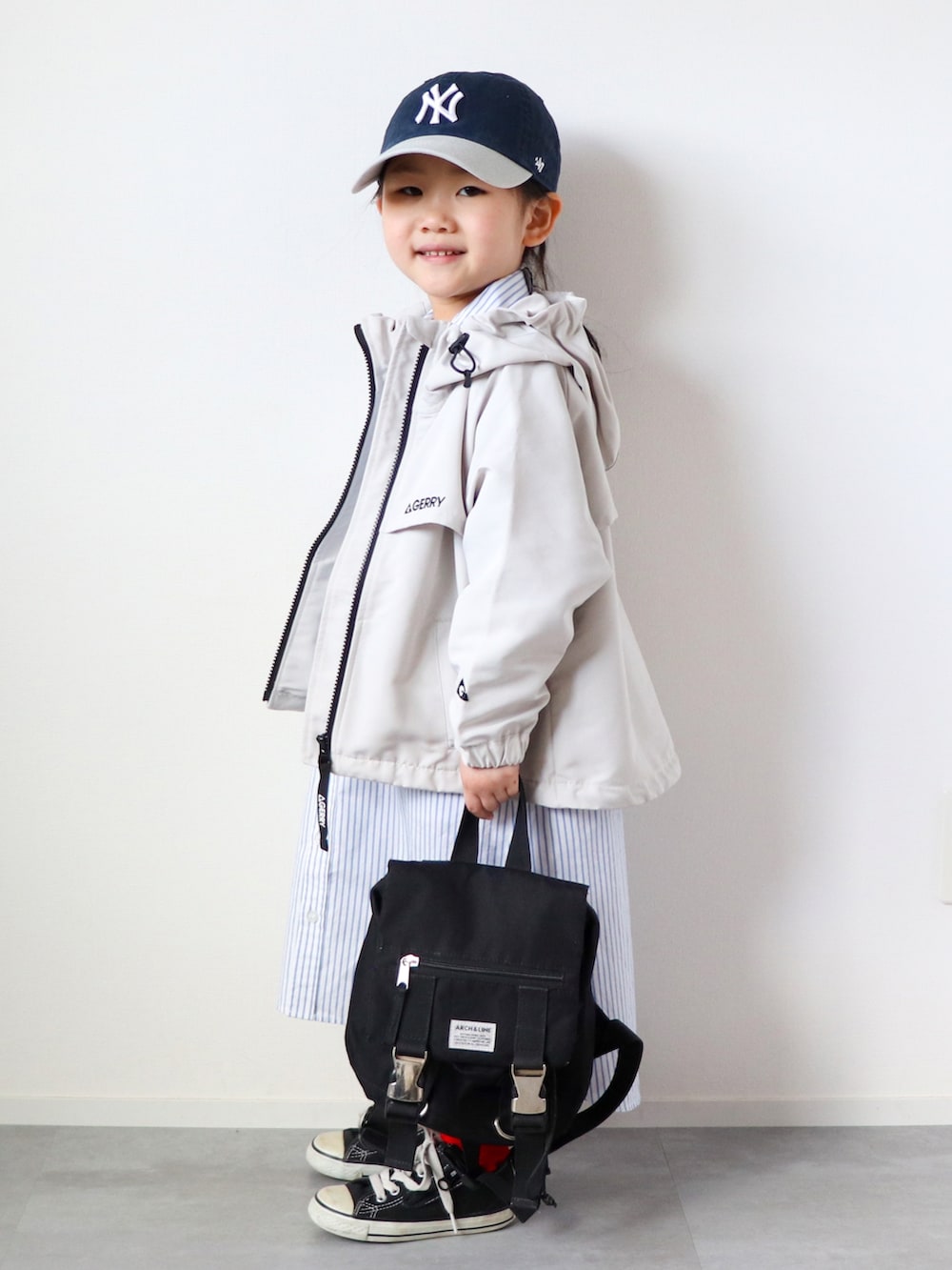 ホワイト系のマウンテンパーカー、ブルー系のシャツワンピース、ブラック系のスニーカーを着用したキッズの春コーディネートの2枚目の写真