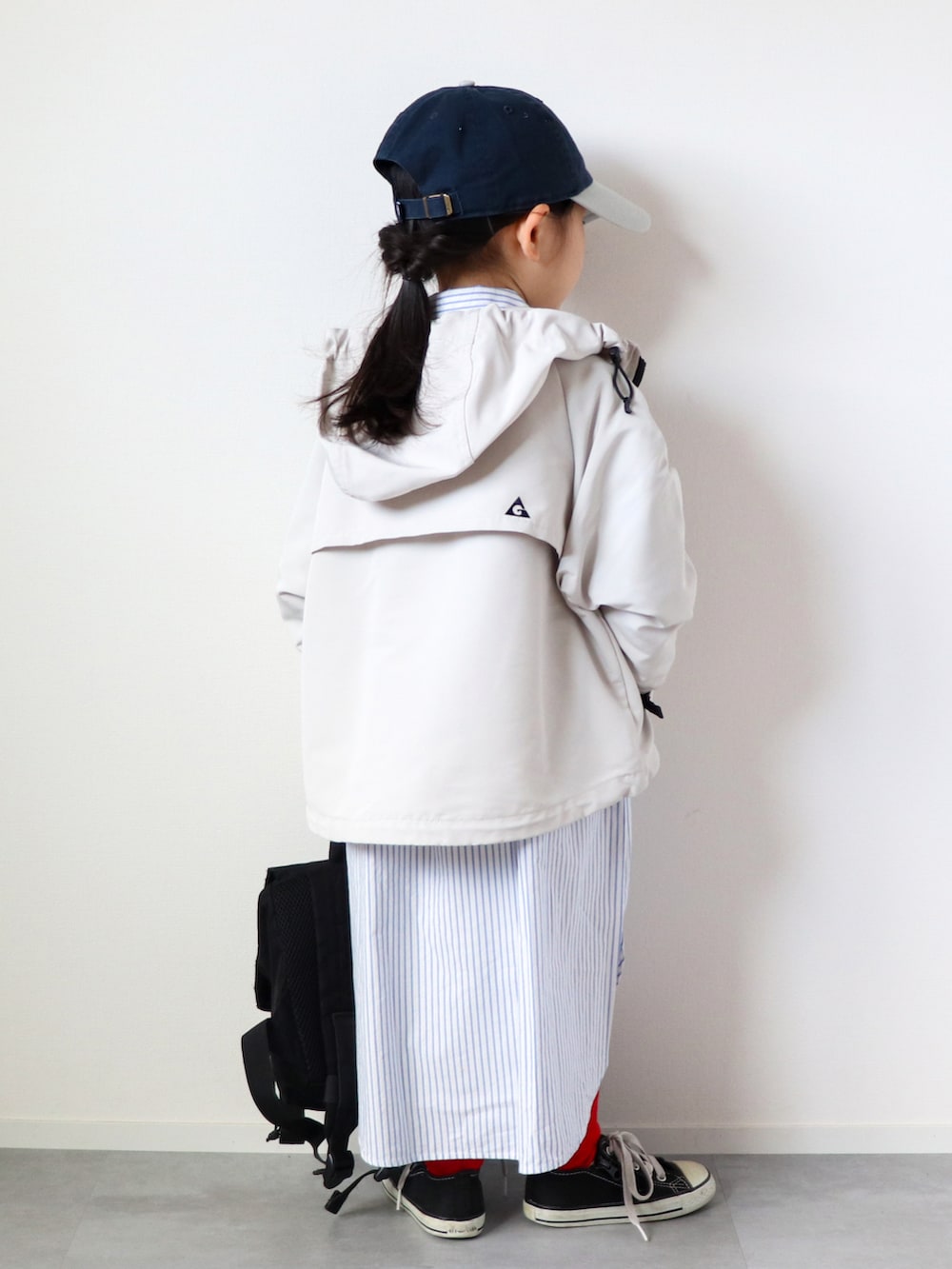 ホワイト系のマウンテンパーカー、ブルー系のシャツワンピース、ブラック系のスニーカーを着用したキッズの春コーディネートの3枚目の写真