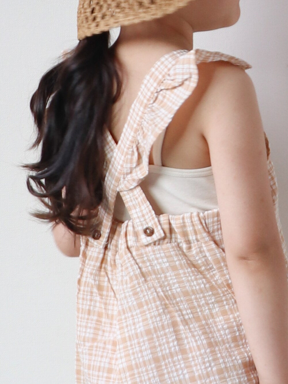 ベージュ系のサロペット/オーバーオール、ベージュ系のキャミソール、ブラウン系のサンダルを着用したキッズの春コーディネートの2枚目の写真