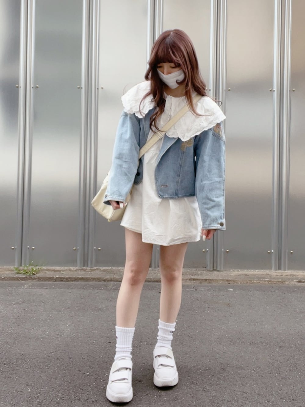 ホワイト系のチュニック、ブルー系のデニムジャケット、ホワイト系のショルダーバッグを着用したレディースの春コーディネートの3枚目の写真