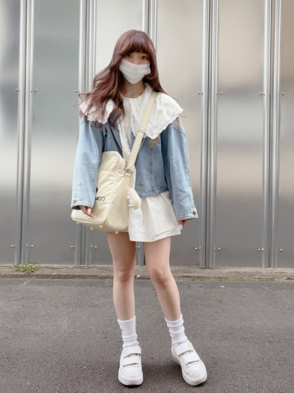 ホワイト系のチュニック、ブルー系のデニムジャケット、ホワイト系のショルダーバッグを着用したレディースの春コーディネートの2枚目の写真