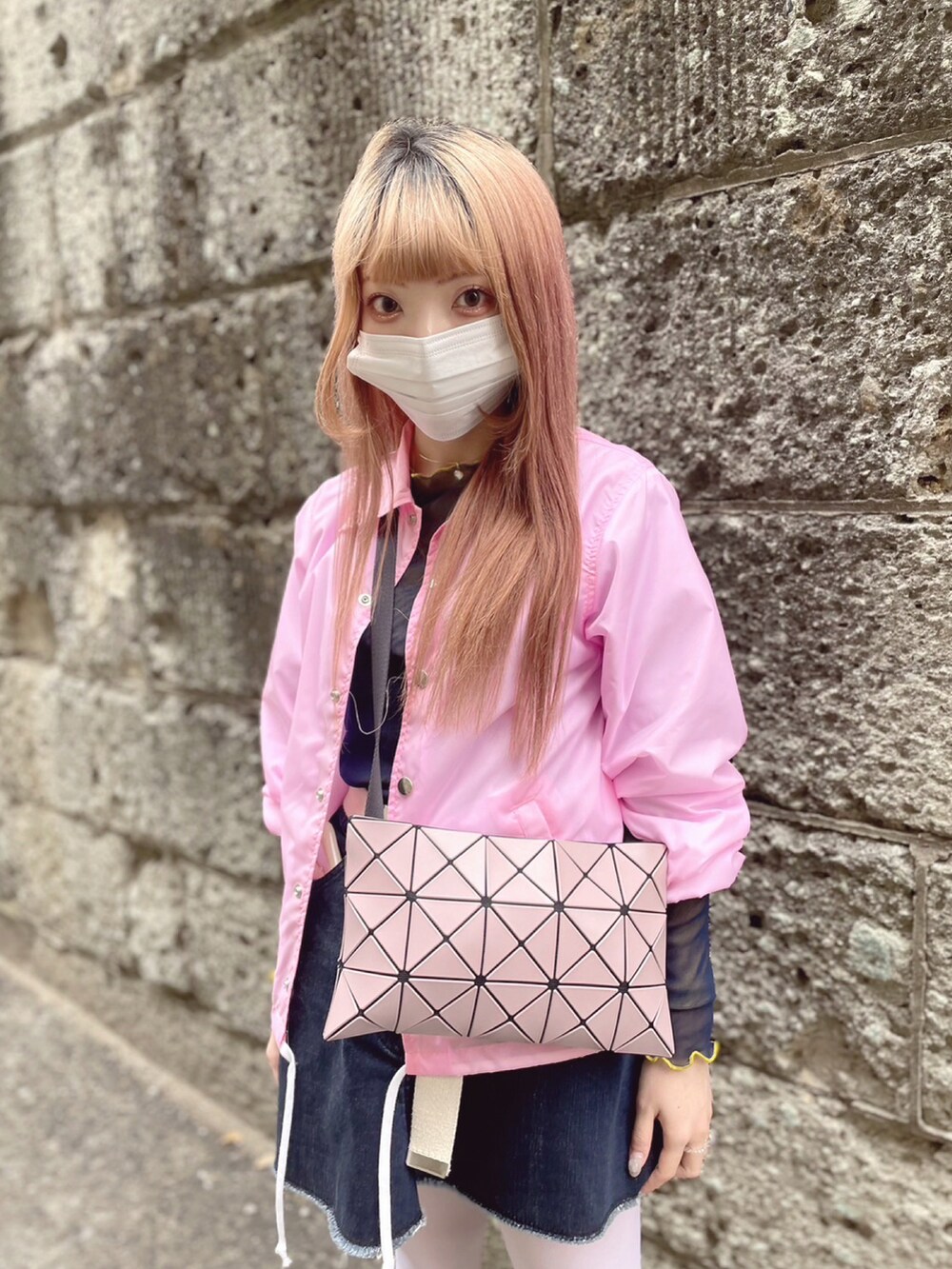 ピンク系のナイロンジャケット、パープル系のバッグ、ブルー系のデニムスカートを着用したレディースの春コーディネートの4枚目の写真