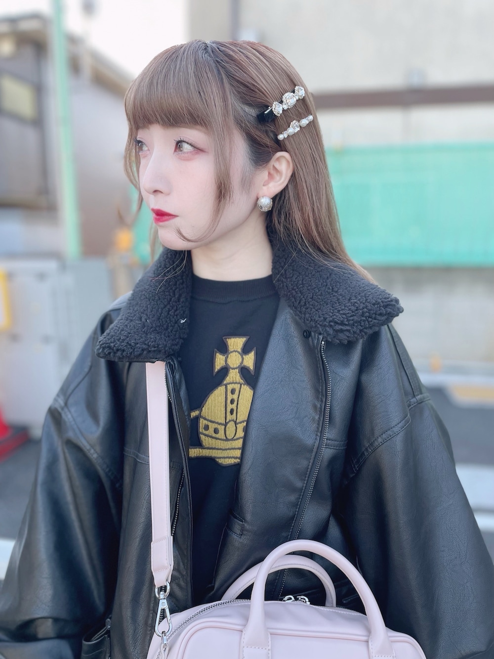 ブラック系のライダースジャケット、ピンク系のショルダーバッグ、ホワイト系のスカートを着用したレディースの冬コーディネートの2枚目の写真