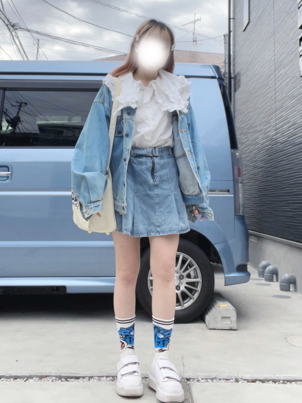 ホワイト系のスニーカー、ブルー系のデニムスカート、ホワイト系のショルダーバッグを着用したレディースの春コーディネートの3枚目の写真