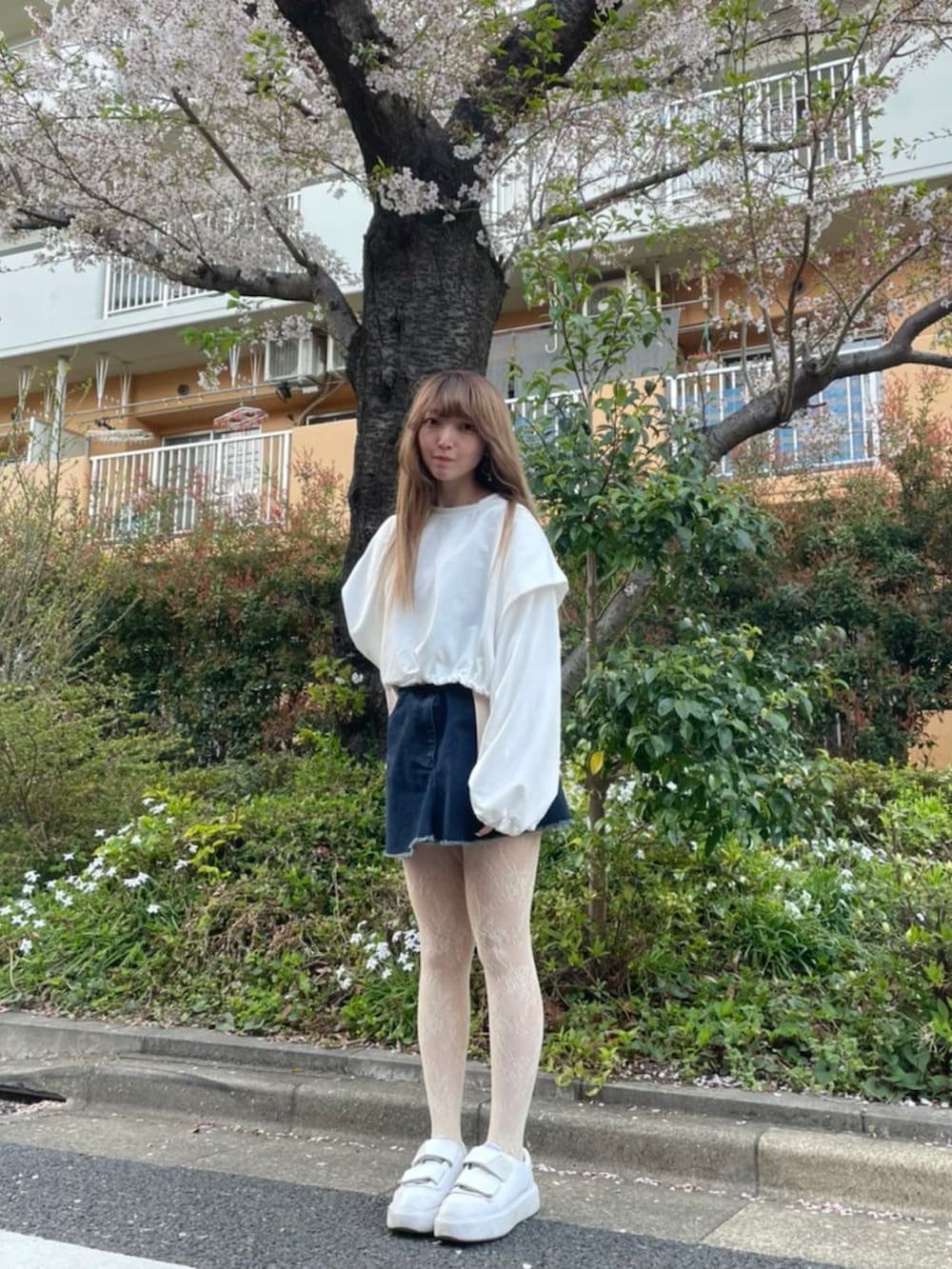 ホワイト系のスウェット、ブルー系のデニムスカート、ホワイト系のスニーカーを着用したレディースの春コーディネートの2枚目の写真