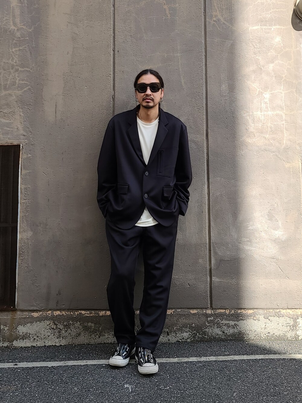 ブラック系のテーラードジャケット、ホワイト系のTシャツ/カットソー、ブラック系のパンツを着用したメンズの春コーディネートの2枚目の写真