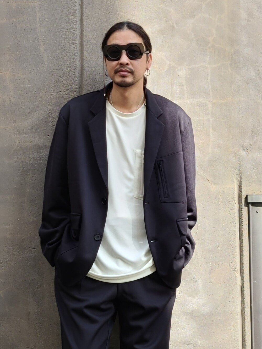 ブラック系のテーラードジャケット、ホワイト系のTシャツ/カットソー、ブラック系のパンツを着用したメンズの春コーディネートの3枚目の写真
