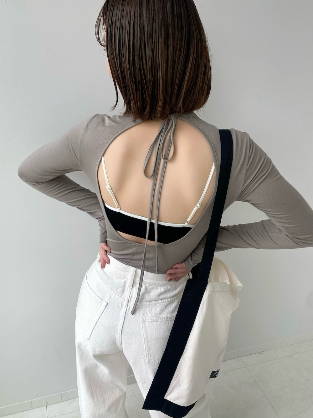 ホワイト系のバッグ、ホワイト系のデニムパンツ、ブラック系のブラジャーを着用したレディースの春コーディネートの2枚目の写真