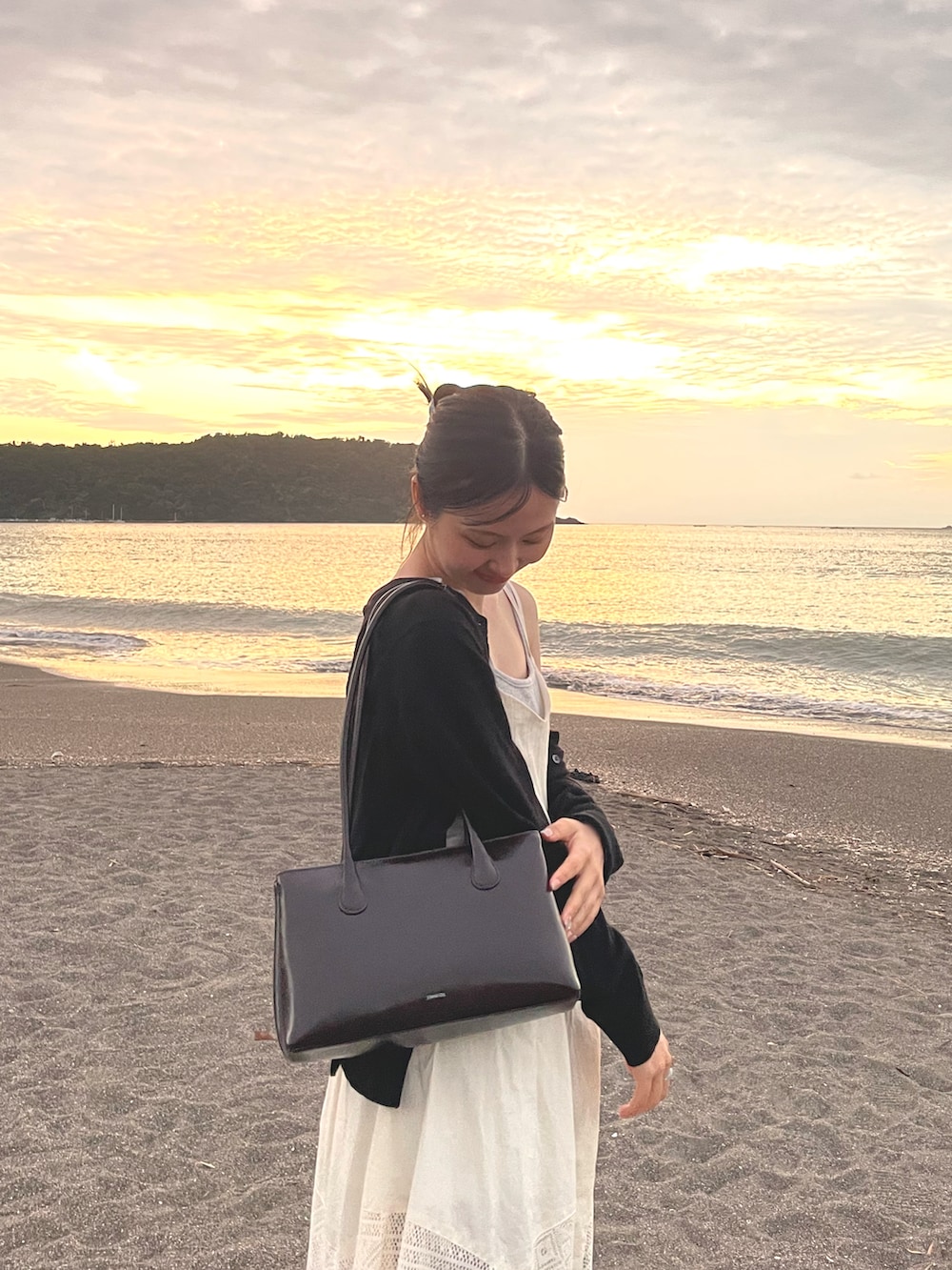 グレー系のスウェットパンツ、ホワイト系のチュニック、シルバー系のサンダルを着用したレディースの秋コーディネートの2枚目の写真