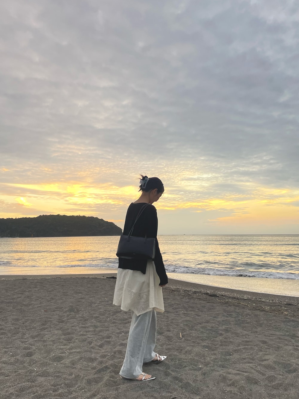 グレー系のスウェットパンツ、ホワイト系のチュニック、シルバー系のサンダルを着用したレディースの秋コーディネートの3枚目の写真