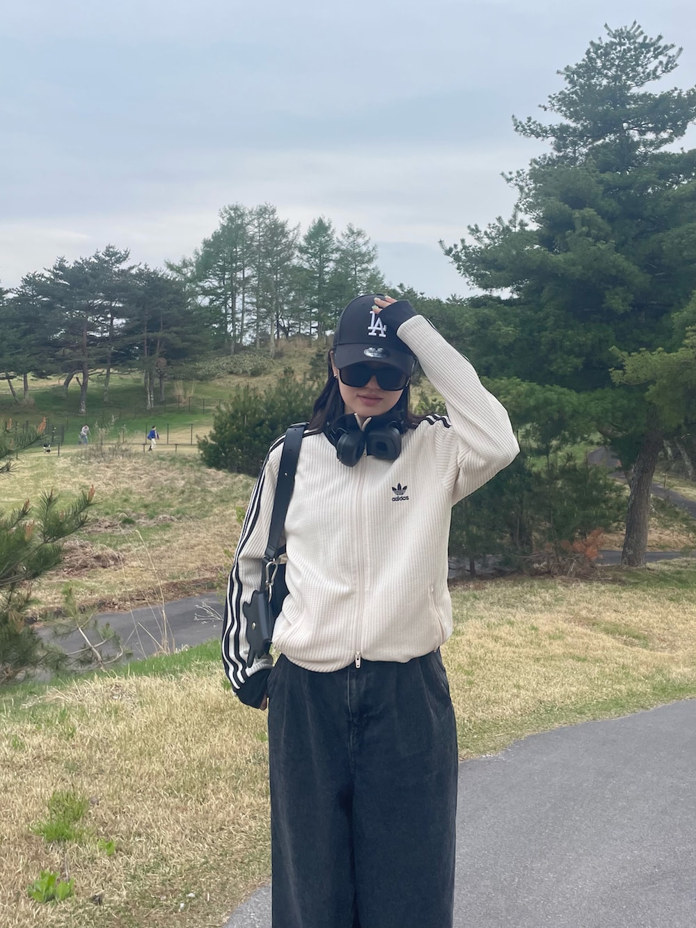 ブラック系のデニムパンツ、ホワイト系のジャージ、ブラック系のスニーカーを着用したレディースの春コーディネートの2枚目の写真