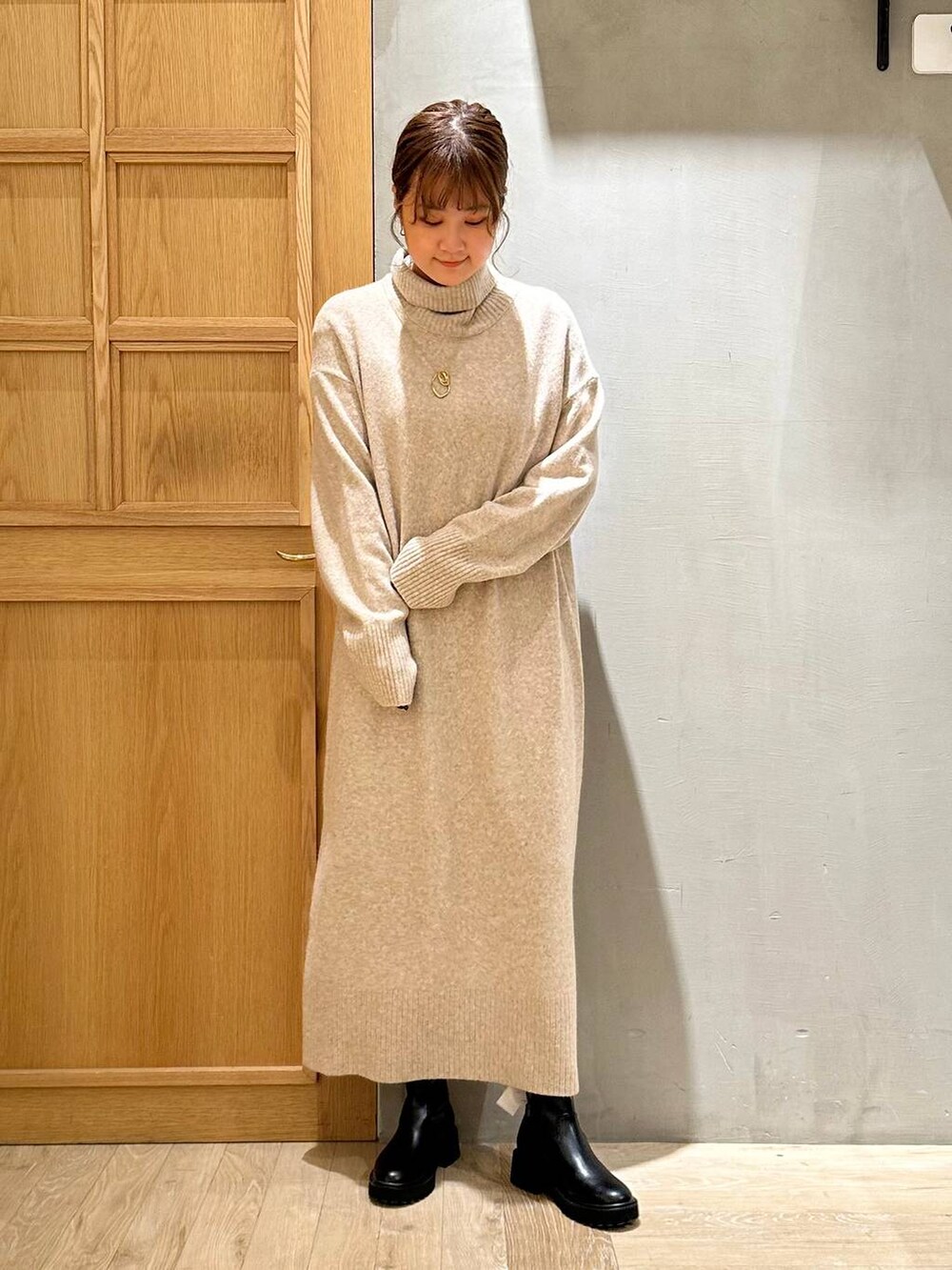 ブラック系のショルダーバッグ、ブラック系のブーツ、ベージュ系のワンピースを着用したレディースの冬コーディネートの2枚目の写真