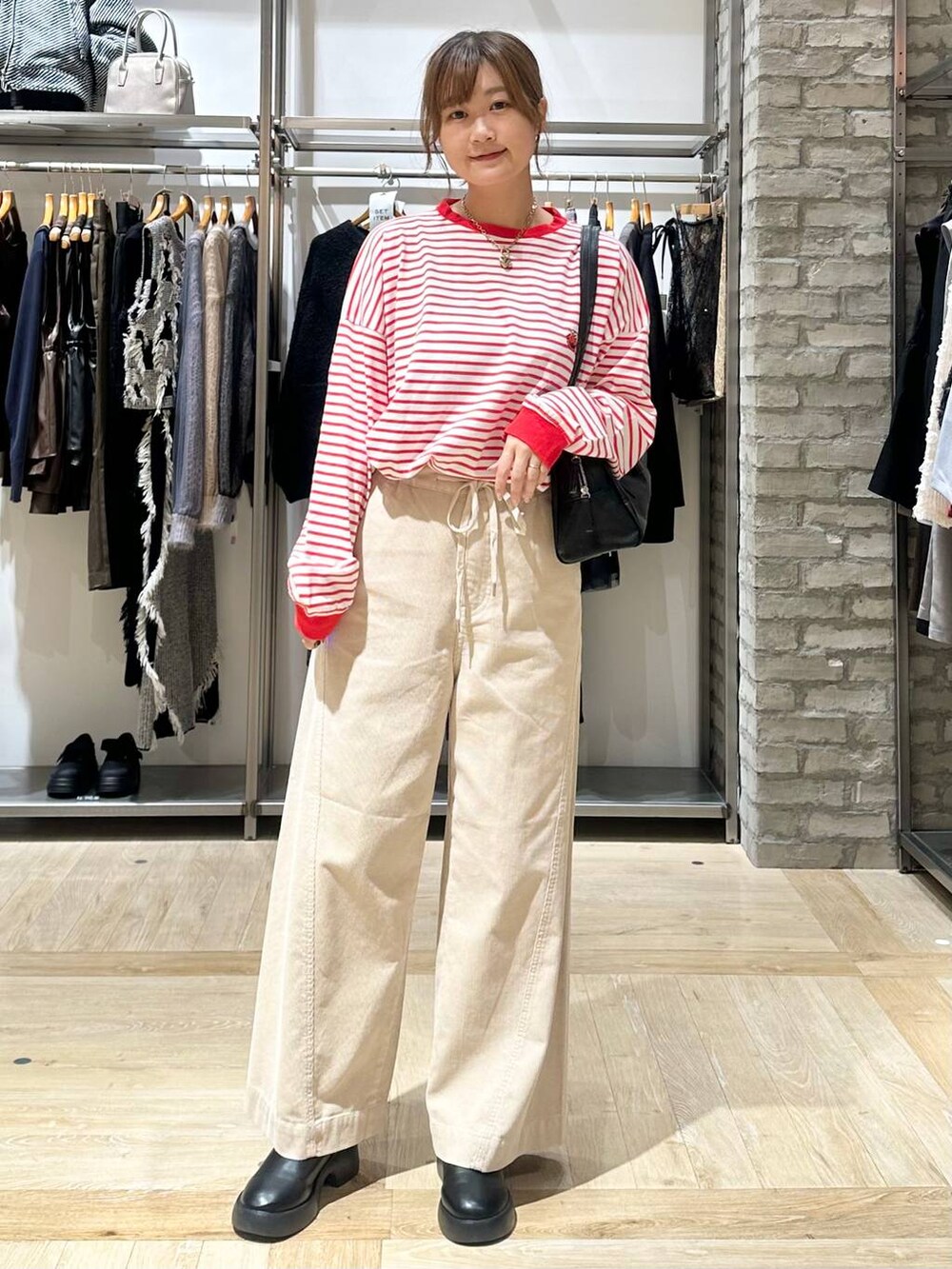 レッド系のTシャツ/カットソー、ブラック系のサンダル、ホワイト系のその他パンツを着用したレディースの秋コーディネートの2枚目の写真