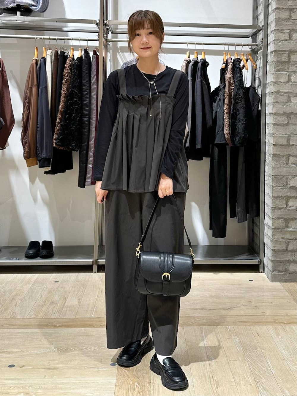 ブラック系のスニーカー、ブラック系のショルダーバッグ、グレー系のサロペット/オーバーオールを着用したレディースの秋コーディネートの2枚目の写真