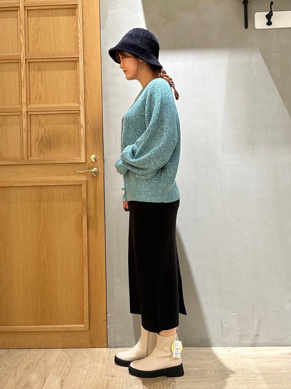 ブラック系のスカート、ホワイト系のブーツ、シルバー系のショルダーバッグを着用したレディースの秋コーディネートの3枚目の写真