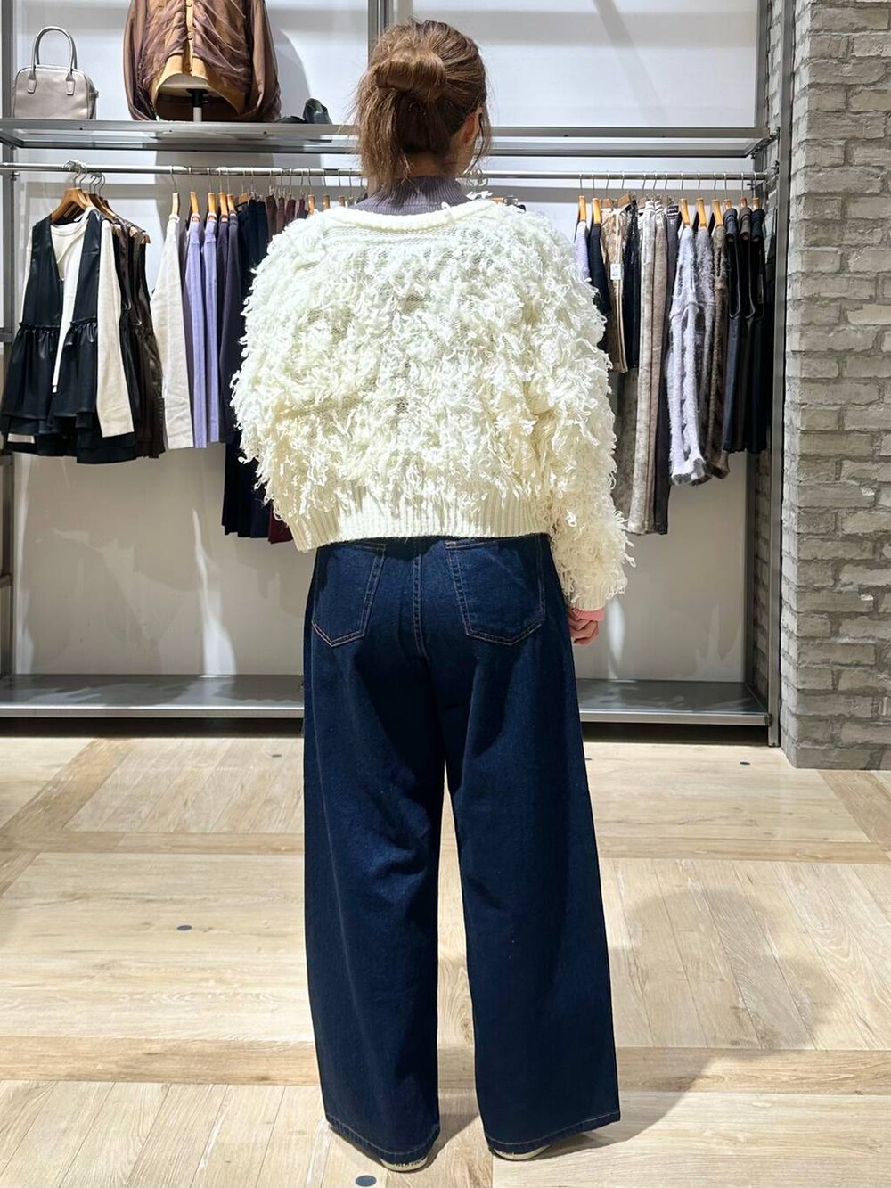 ブルー系のデニムパンツ、グレー系のニット/セーター、ブラック系のボストンバッグを着用したレディースの秋コーディネートの4枚目の写真