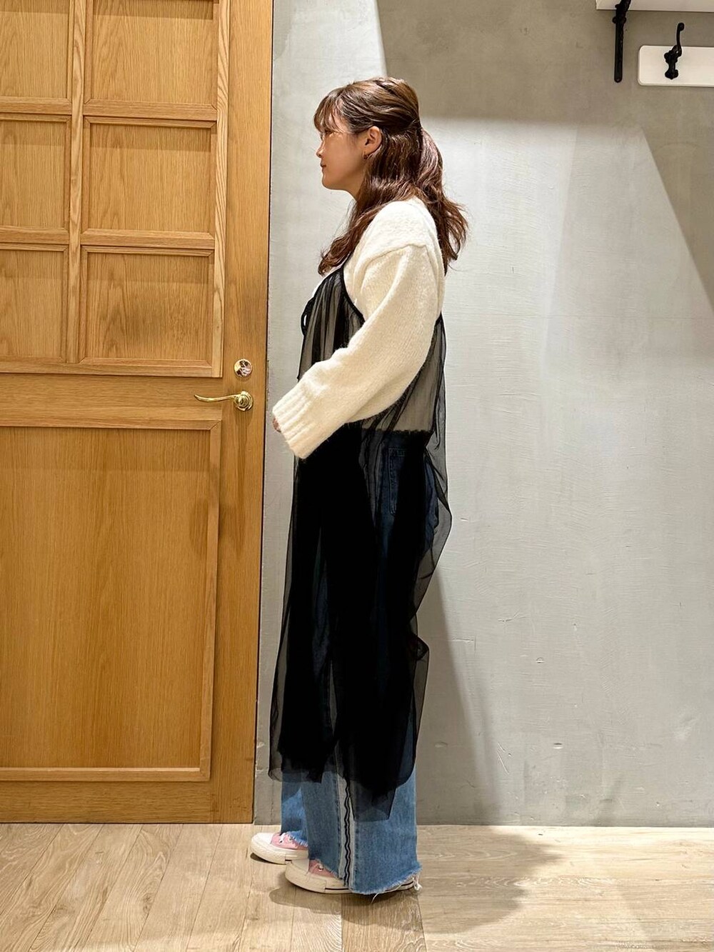 ブルー系のデニムパンツ、ホワイト系のニット/セーター、ブラック系のワンピースを着用したレディースの冬コーディネートの2枚目の写真