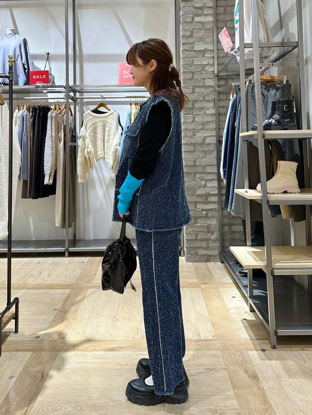 ブラック系のスニーカー、ブルー系のベスト、ブルー系のデニムパンツを着用したレディースの冬コーディネートの3枚目の写真