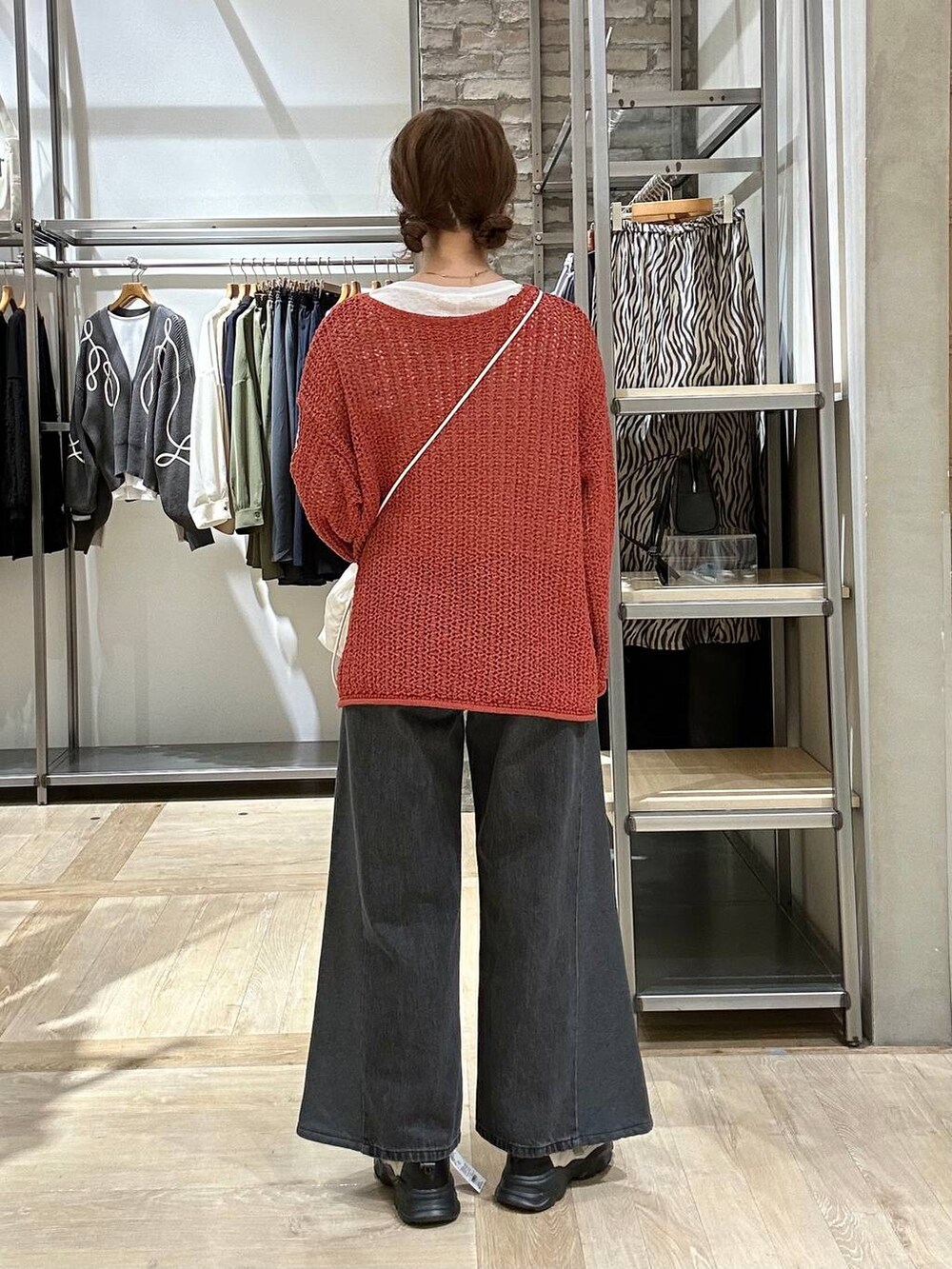 レッド系のニット/セーター、ホワイト系のショルダーバッグ、ホワイト系のスニーカーを着用したレディースの春コーディネートの3枚目の写真