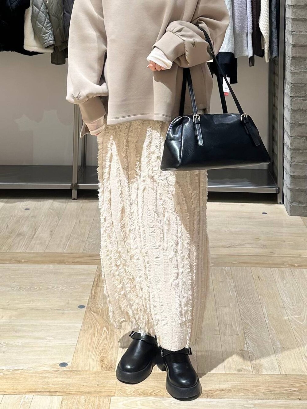 ブラック系のサンダル、ブラック系のボストンバッグ、ホワイト系のスカートを着用したレディースの冬コーディネートの5枚目の写真