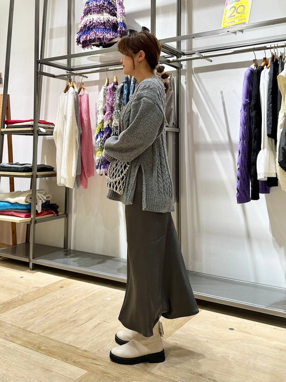 ホワイト系のブーツ、グレー系のスカート、グレー系のショルダーバッグを着用したレディースの秋コーディネートの2枚目の写真