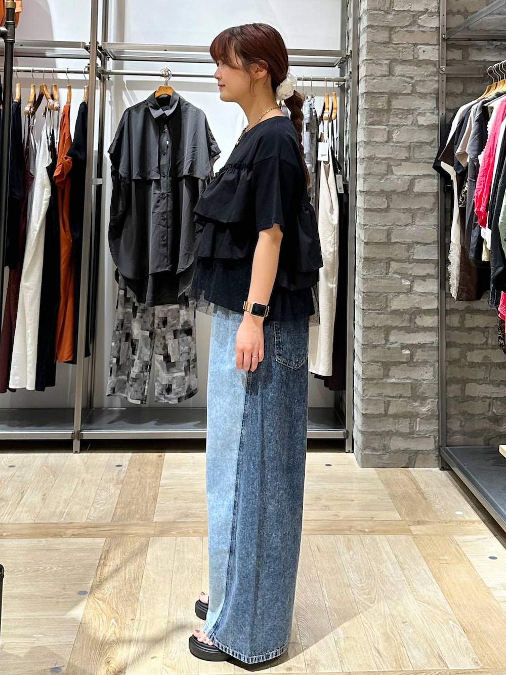 ブルー系のデニムパンツ、ブラック系のサンダル、ブラック系のTシャツ/カットソーを着用したレディースの夏コーディネートの2枚目の写真