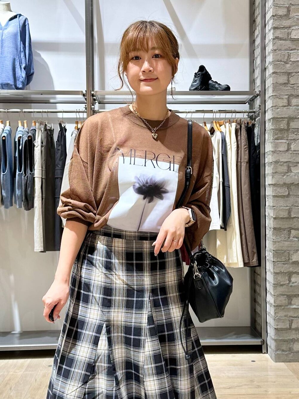 ブラウン系のニット/セーター、ブラック系のスカート、ブラック系のスニーカーを着用したレディースの秋コーディネートの4枚目の写真