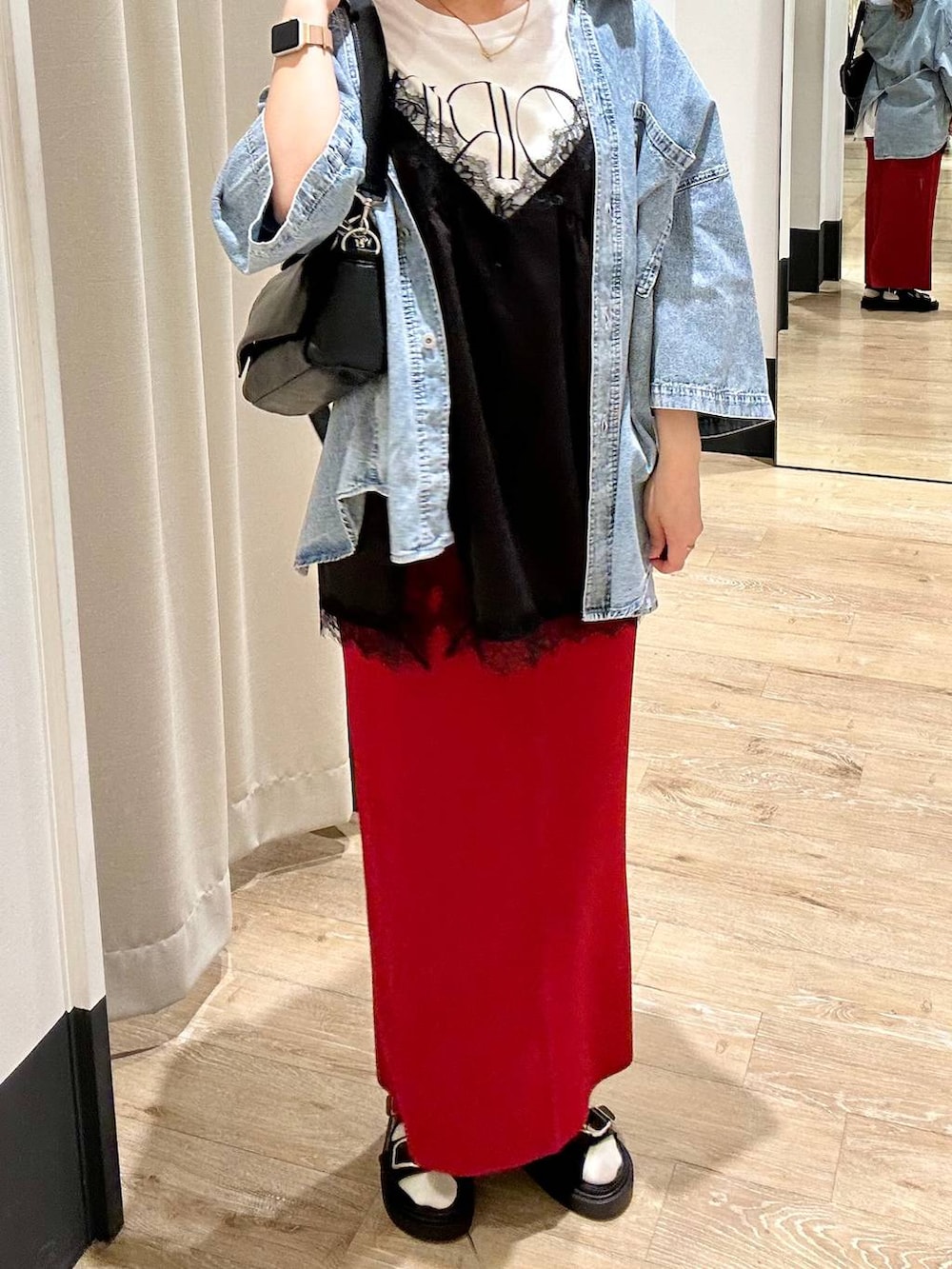 レッド系のスカート、ブラック系のショルダーバッグ、ブラック系のサンダルを着用したレディースの春コーディネートの5枚目の写真