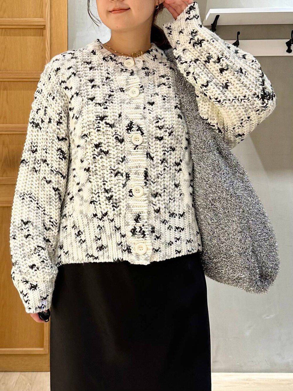 シルバー系のショルダーバッグ、ブラック系のスカート、ブラック系のブーツを着用したレディースの秋コーディネートの5枚目の写真