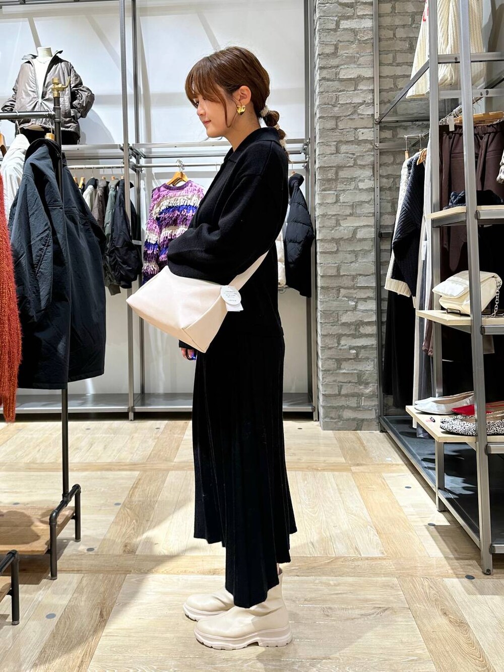 ホワイト系のブーツ、ホワイト系のショルダーバッグ、ブラック系のワンピースを着用したレディースの秋コーディネートの3枚目の写真