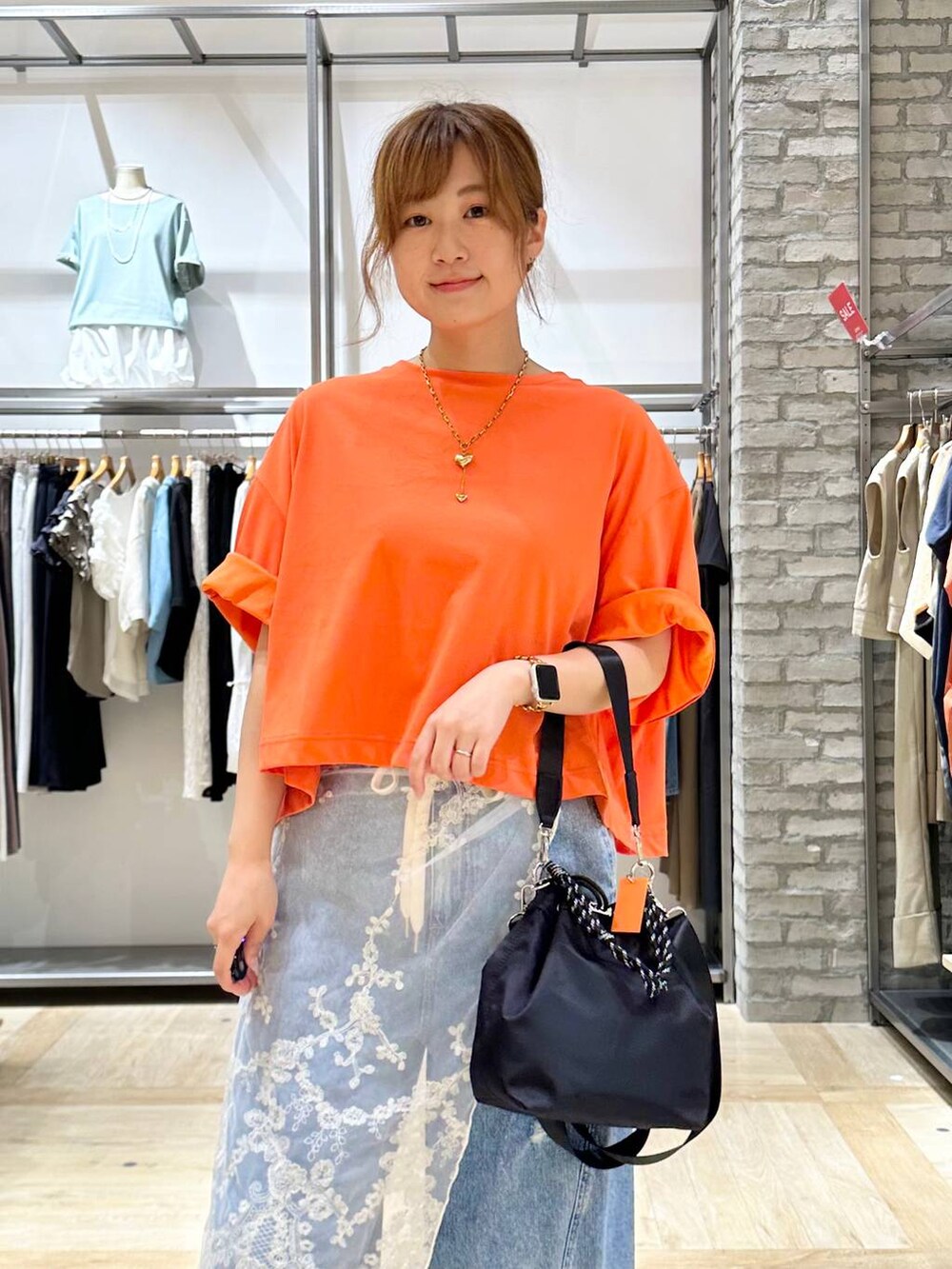 ブラック系のサンダル、オレンジ系のTシャツ/カットソー、ブルー系のデニムパンツを着用したレディースの夏コーディネートの4枚目の写真