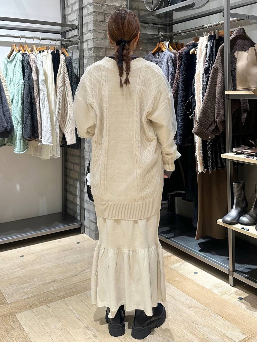 ホワイト系のスカート、グレー系のニット/セーター、ブラック系のブーツを着用したレディースの秋コーディネートの3枚目の写真