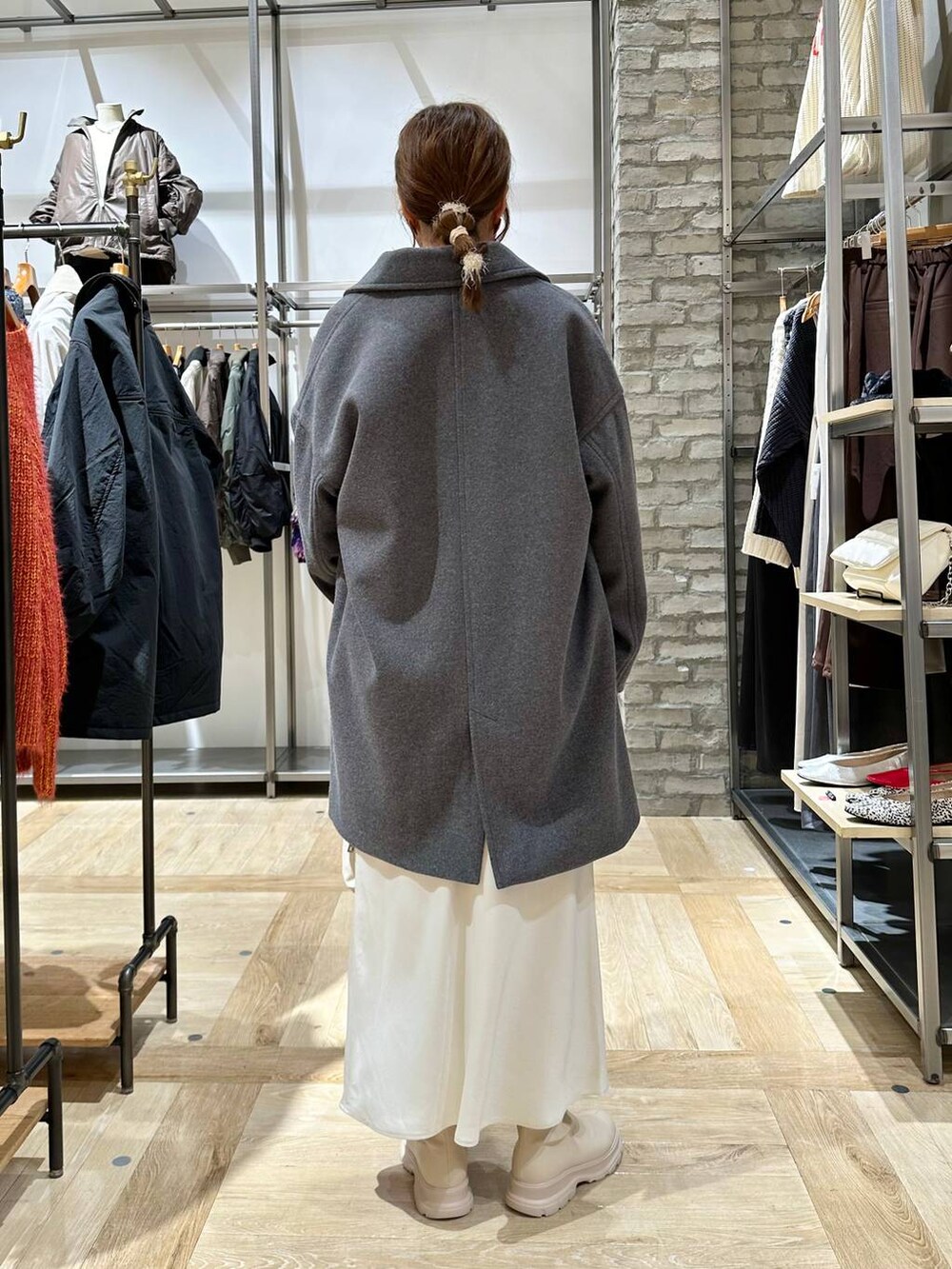 グレー系のその他アウター、ホワイト系のスカート、ホワイト系のブーツを着用したレディースの冬コーディネートの3枚目の写真