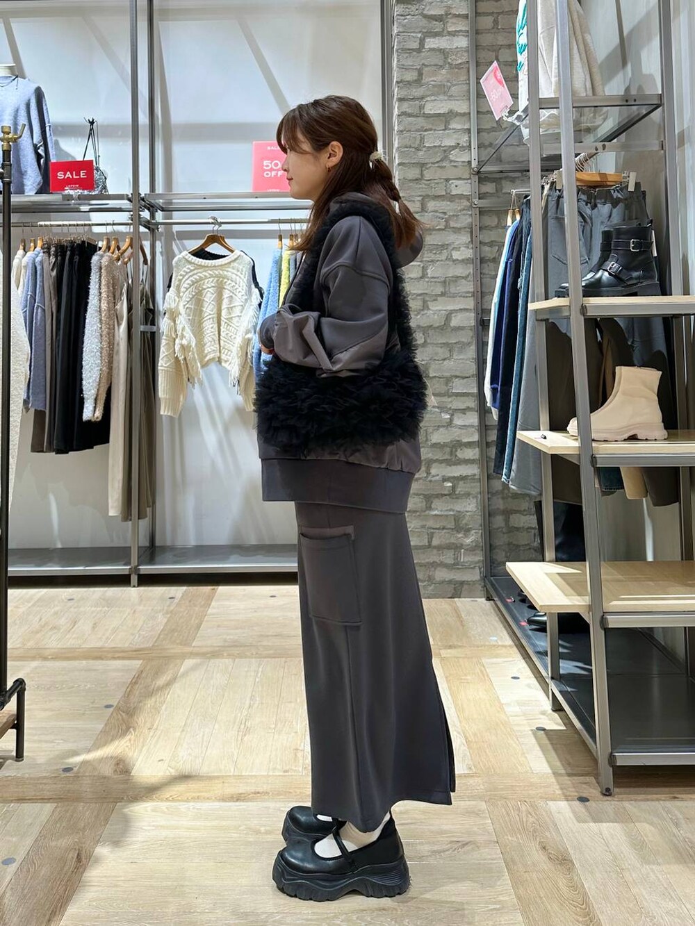 ブラック系のスニーカー、ブラック系のショルダーバッグ、グレー系のスカートを着用したレディースの冬コーディネートの2枚目の写真