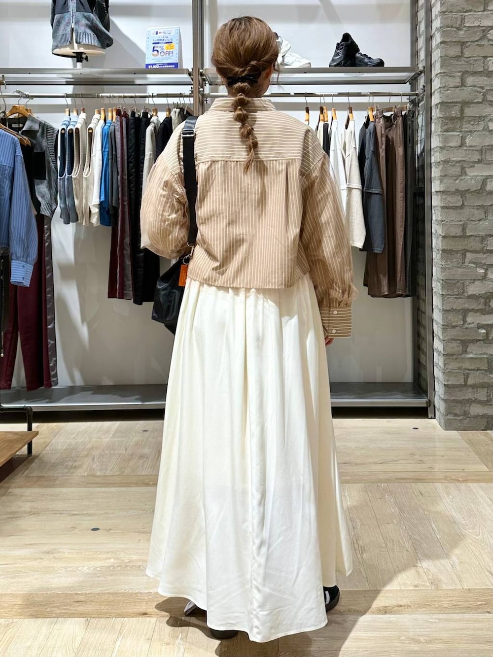 ブラック系のショルダーバッグ、ホワイト系のスカート、イエロー系のシャツ/ブラウスを着用したレディースの秋コーディネートの3枚目の写真