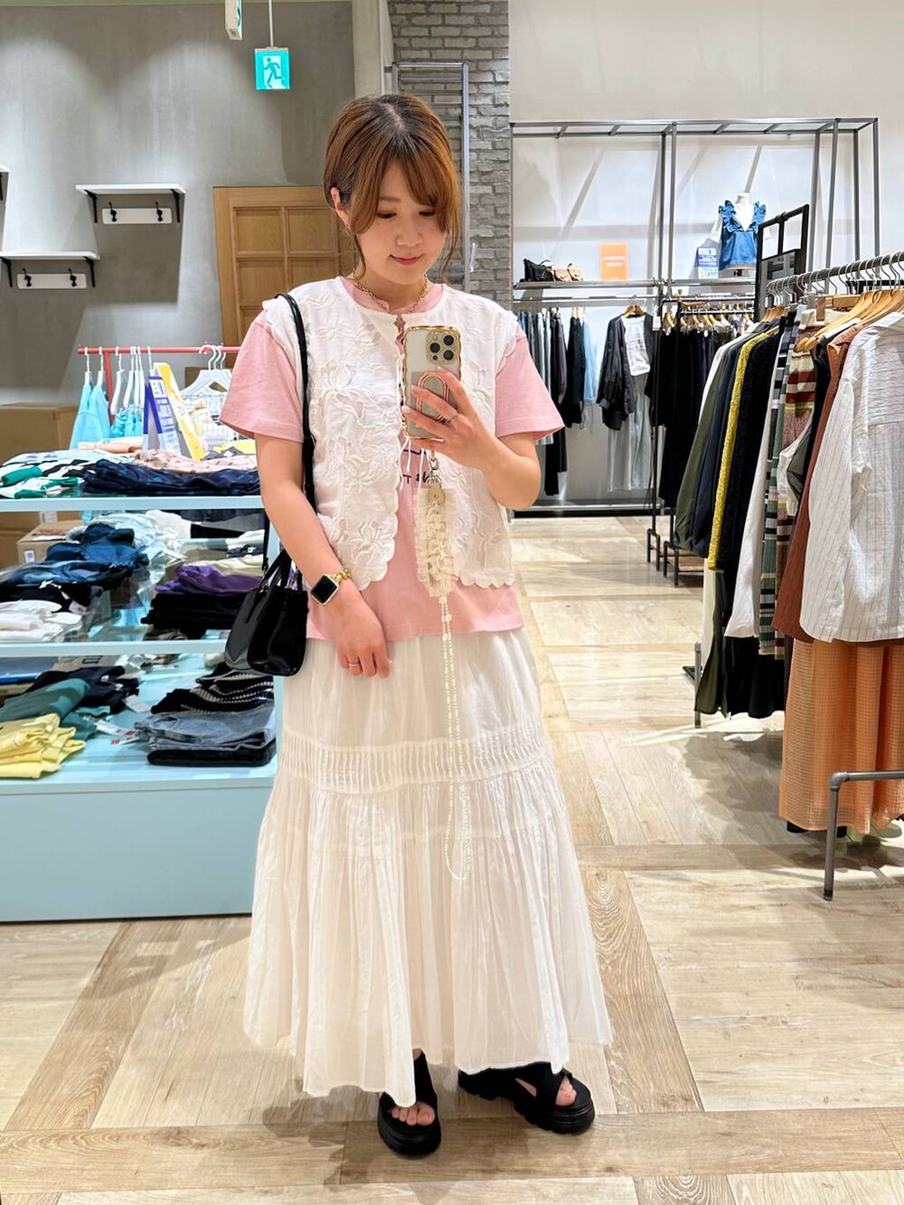 ホワイト系のベスト、ブラック系のショルダーバッグ、ブラック系のサンダルを着用したレディースの春コーディネートの2枚目の写真