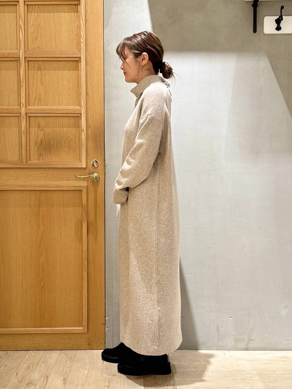 ブラック系のショルダーバッグ、ブラック系のブーツ、ベージュ系のワンピースを着用したレディースの冬コーディネートの4枚目の写真