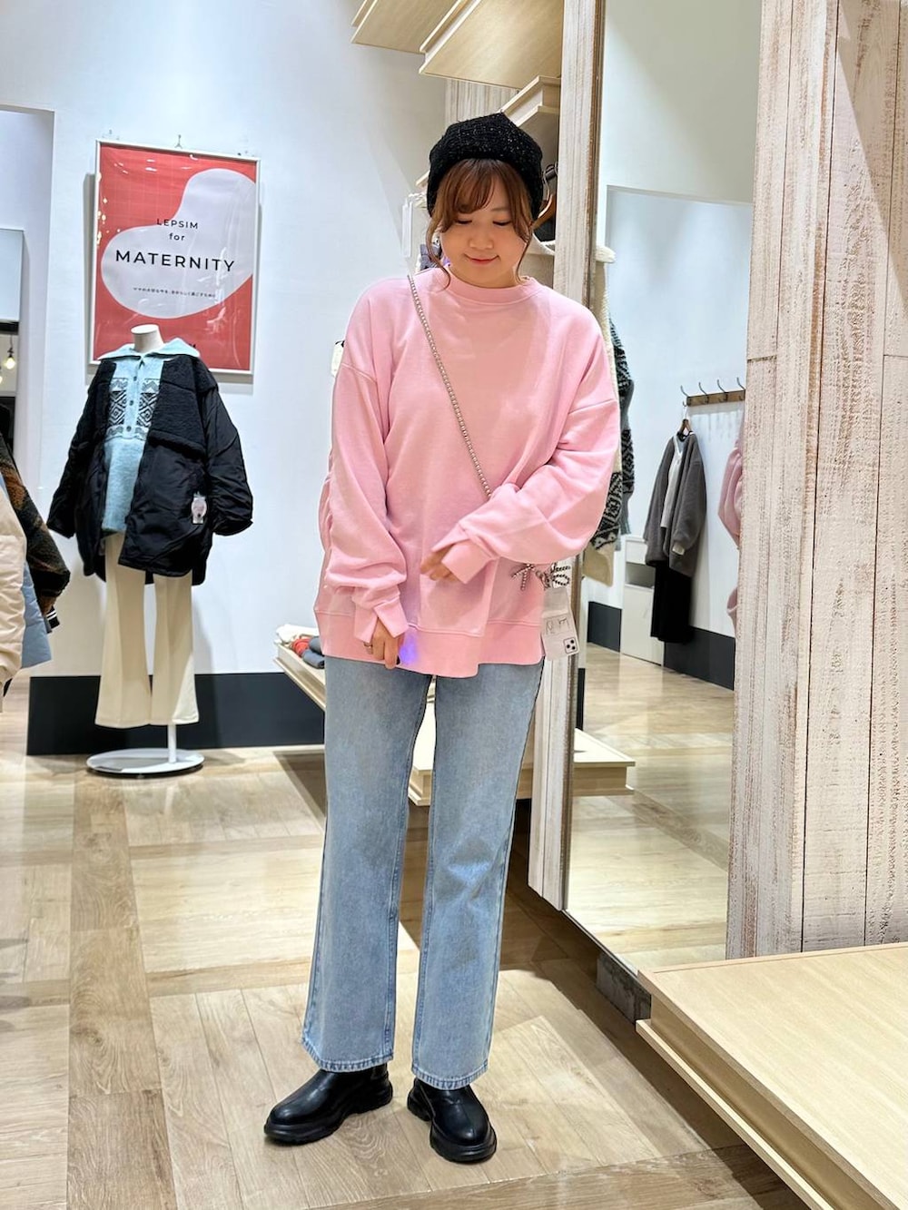 ブルー系のデニムパンツ、ブラック系のブーツ、ピンク系のスウェットを着用したレディースの冬コーディネートの2枚目の写真