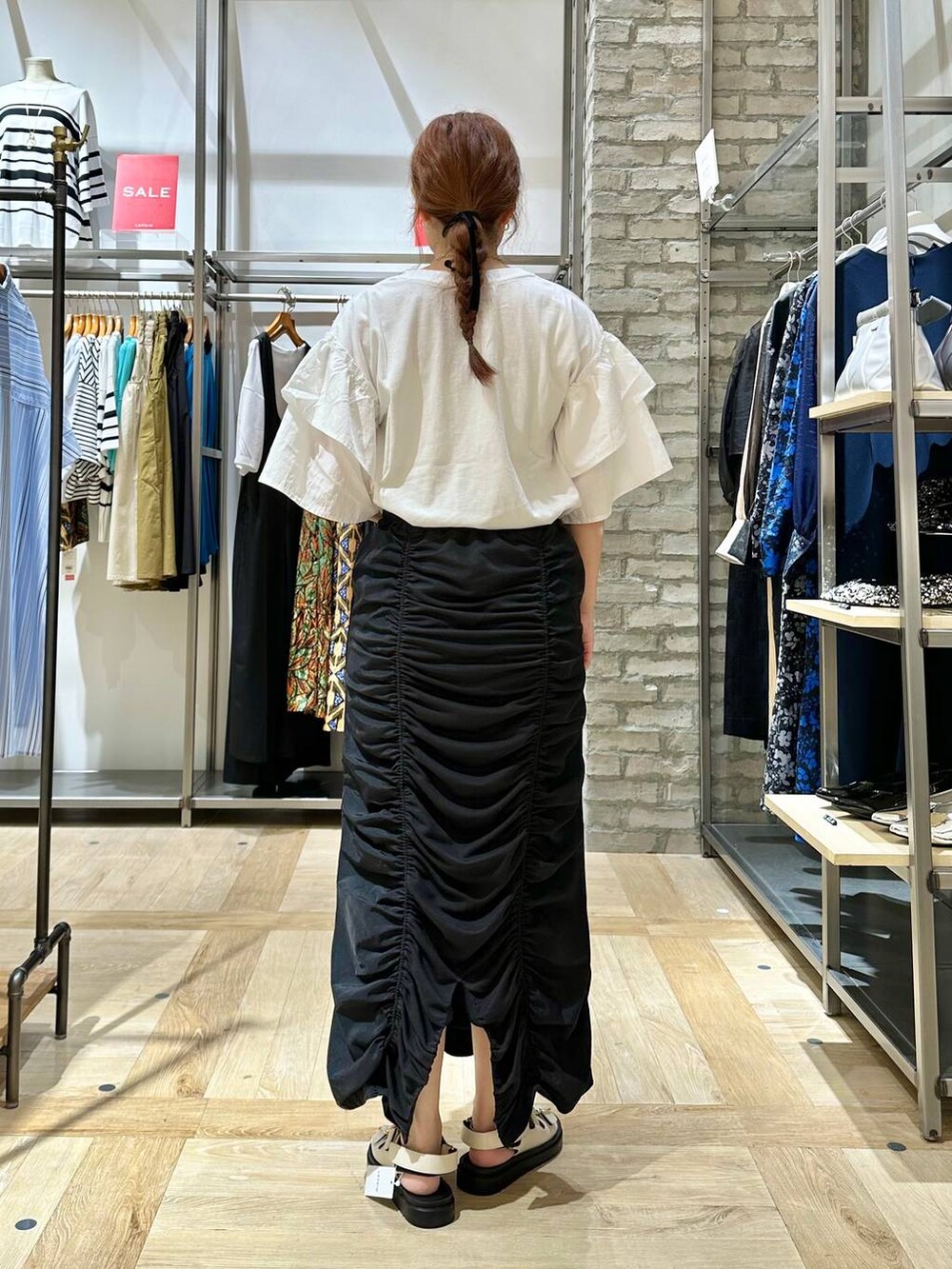 ホワイト系のサンダル、ブラック系のスカート、ホワイト系のTシャツ/カットソーを着用したレディースの夏コーディネートの3枚目の写真