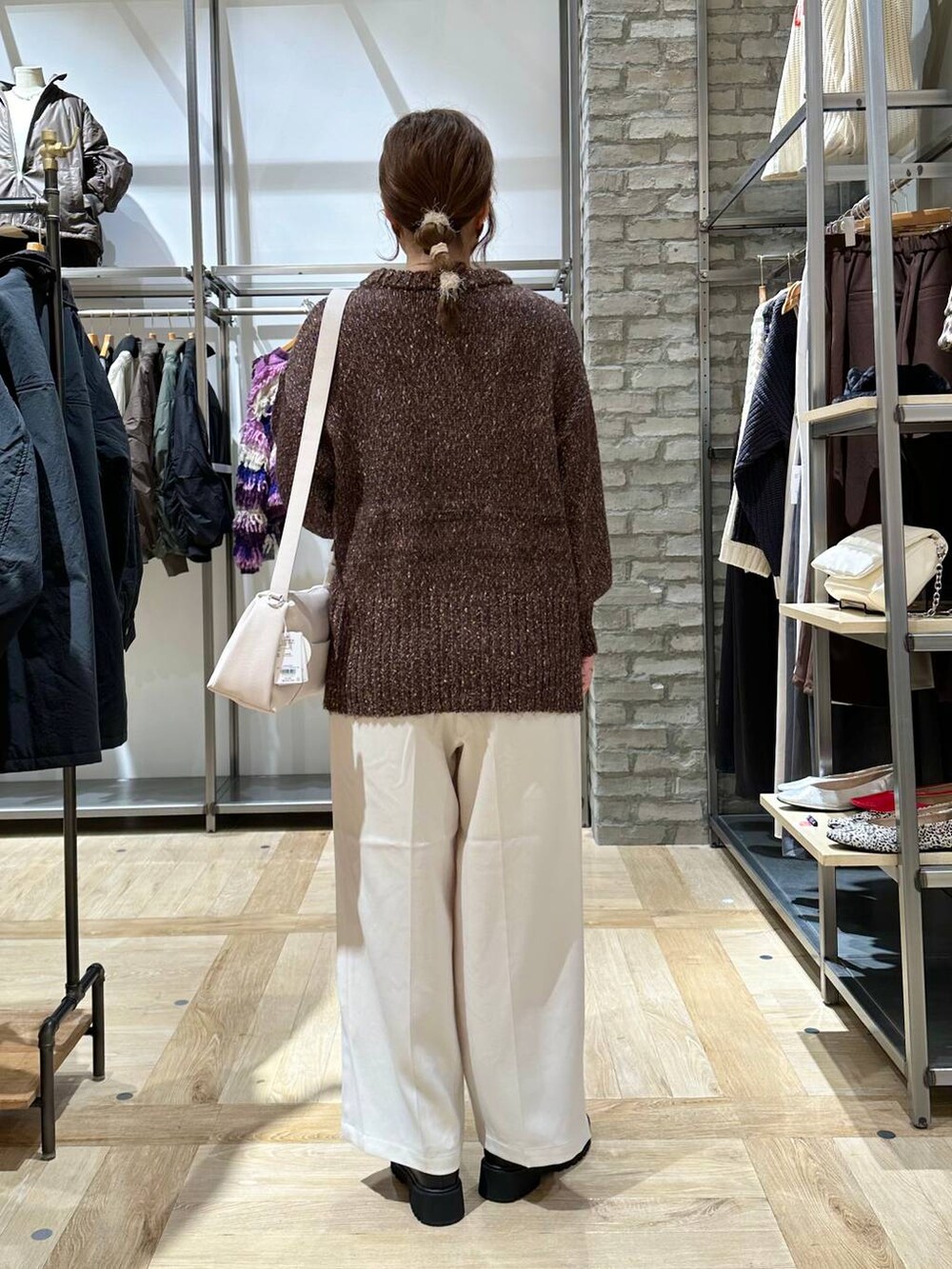 ブラック系のブーツ、ホワイト系のショルダーバッグ、ブラック系のニット/セーターを着用したレディースの秋コーディネートの3枚目の写真