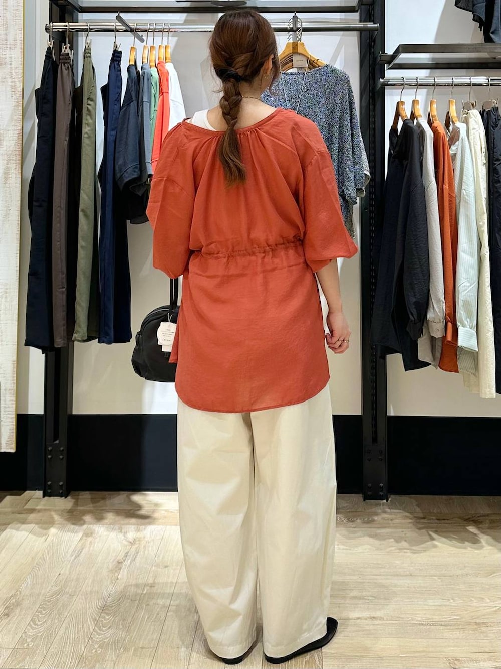 ブラック系のパンプス、オレンジ系のシャツ/ブラウス、グレー系のボストンバッグを着用したレディースの春コーディネートの3枚目の写真
