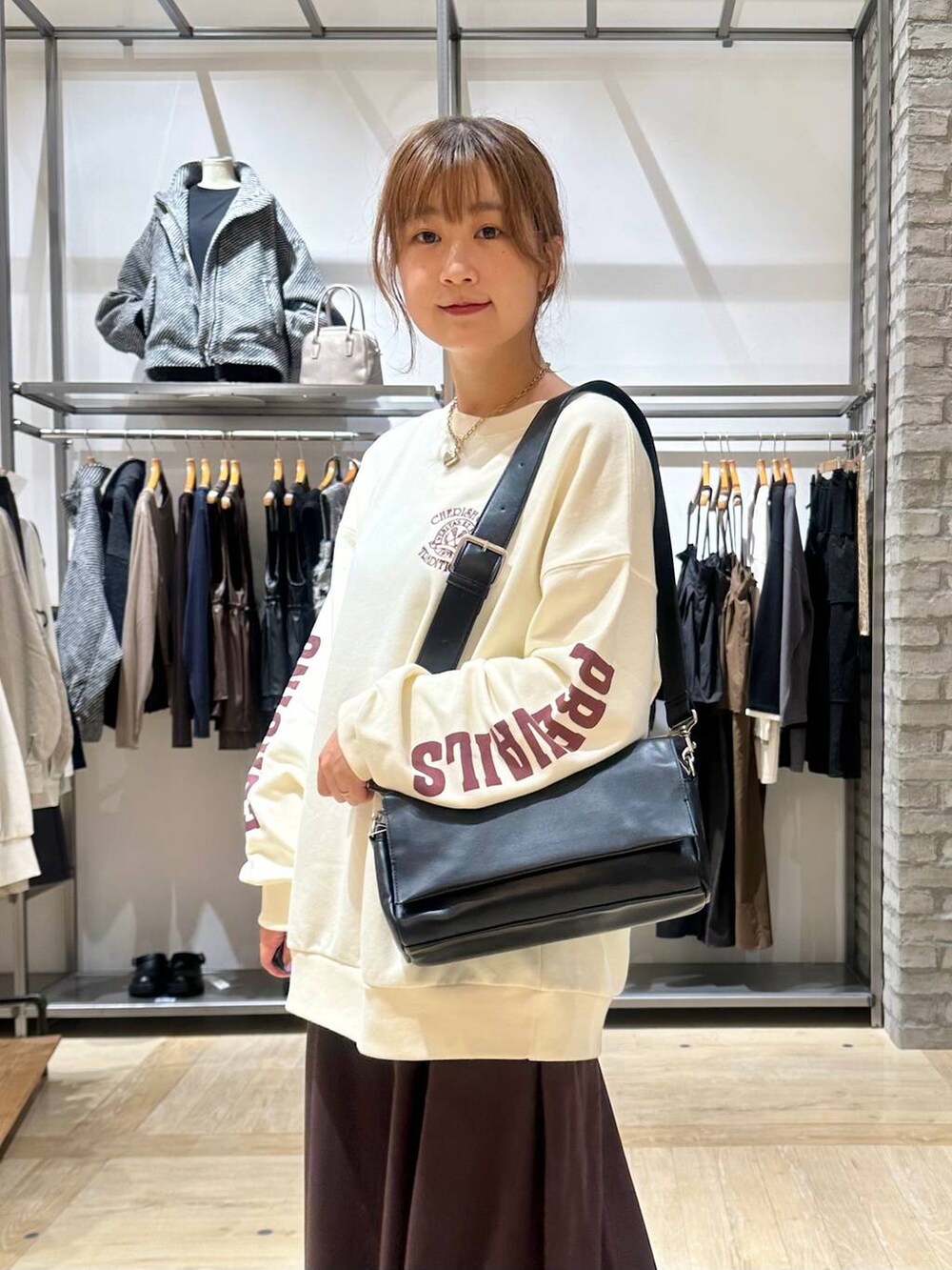 ブラック系のショルダーバッグ、ブラウン系のスカート、ブラック系のブーツを着用したレディースの秋コーディネートの6枚目の写真