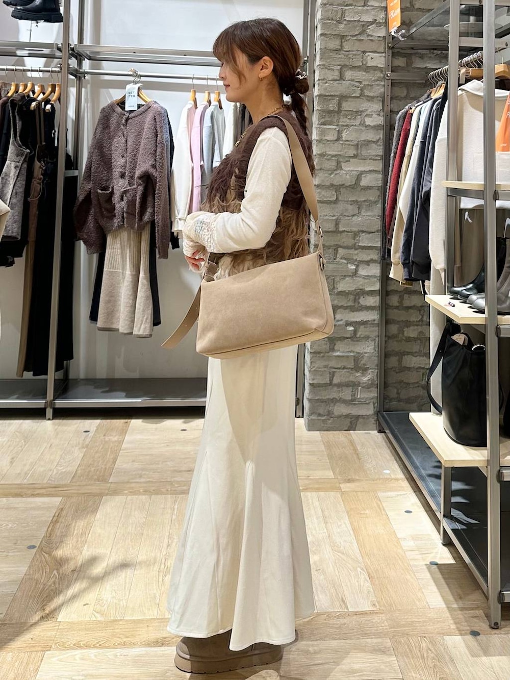 ベージュ系のショルダーバッグ、ベージュ系のブーツ、ブラウン系のベストを着用したレディースの冬コーディネートの2枚目の写真