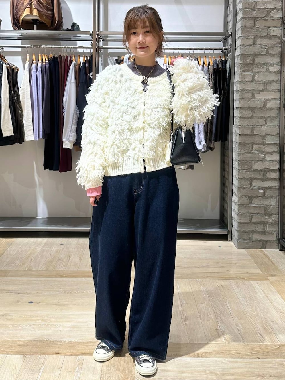 ブルー系のデニムパンツ、グレー系のニット/セーター、ブラック系のボストンバッグを着用したレディースの秋コーディネートの2枚目の写真