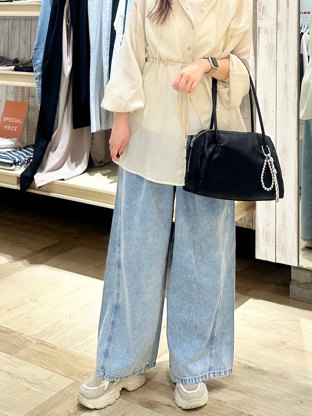 ブルー系のデニムパンツ、ブラック系のボストンバッグ、ホワイト系のシャツ/ブラウスを着用したレディースの春コーディネートの5枚目の写真