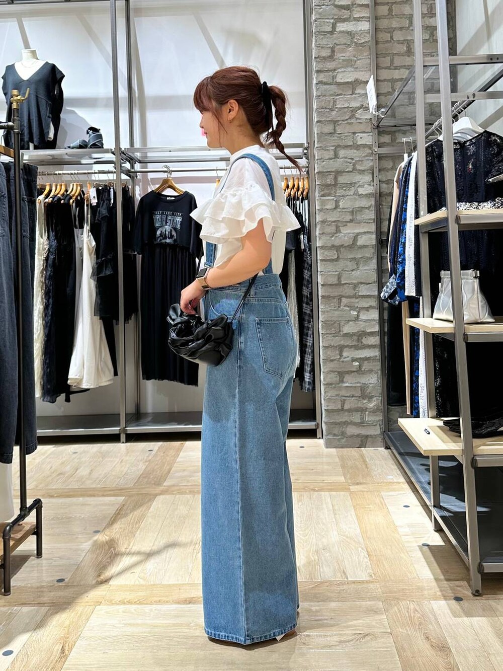 ブラック系のショルダーバッグ、ホワイト系のシャツ/ブラウス、ブルー系のデニムパンツを着用したレディースの夏コーディネートの2枚目の写真