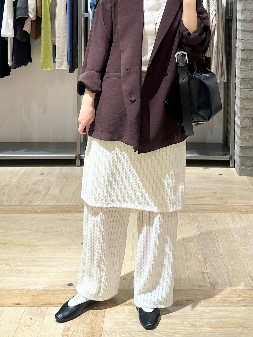 ブラック系のショルダーバッグ、ブラック系のパンプス、ブラウン系のテーラードジャケットを着用したレディースの春コーディネートの5枚目の写真